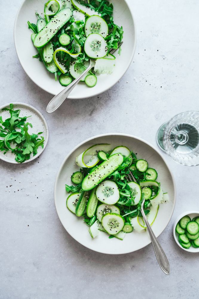 Ensalada de pepino y rúcula en platos blancos
