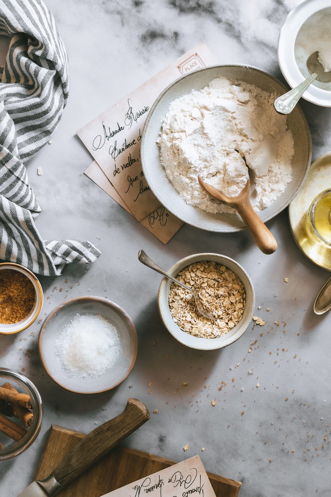 Harina, avena, azúcar, canela y postales manuscritas sobre mármol