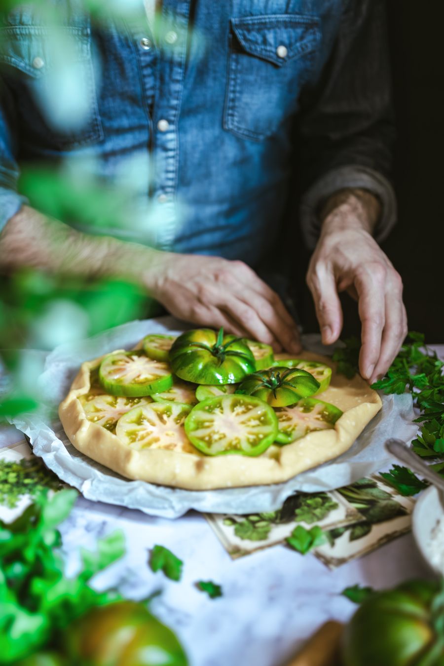 Manos montando una galette de tomate verde