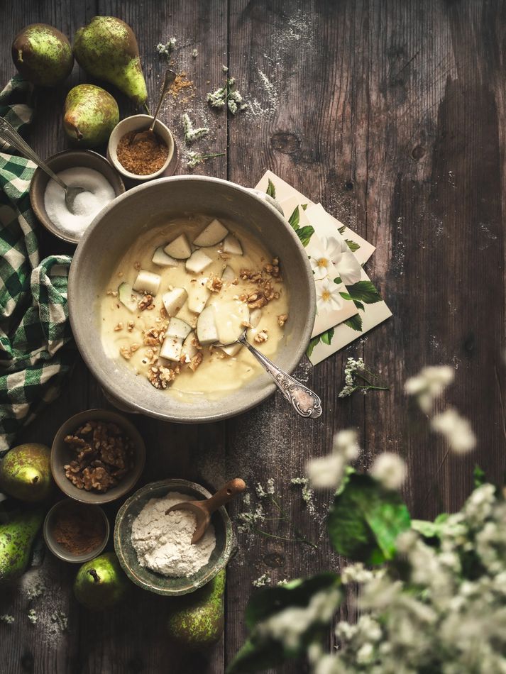 Preparación de masa con peras y flores sobre madera