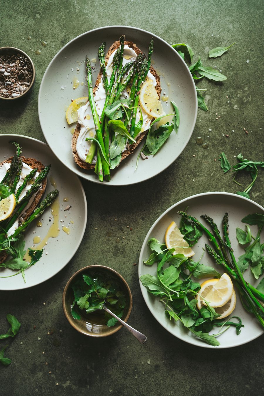 Tostadas con espárragos verdes, queso fresco y limón sobre fondo verde oliva