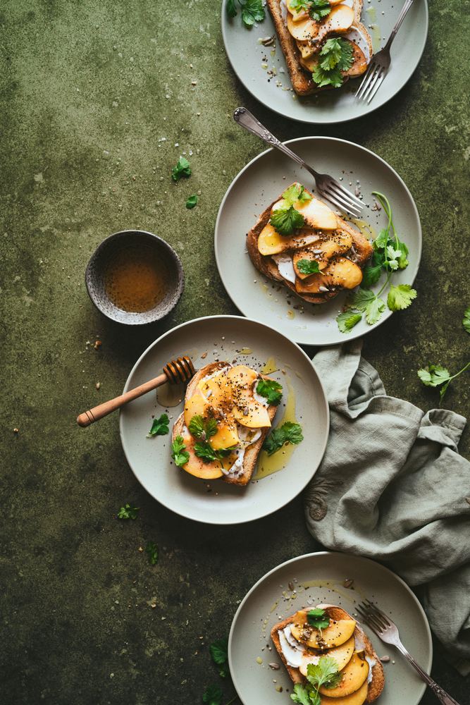 Tostadas con melocotón, miel y hierbas sobre fondo verde oliva